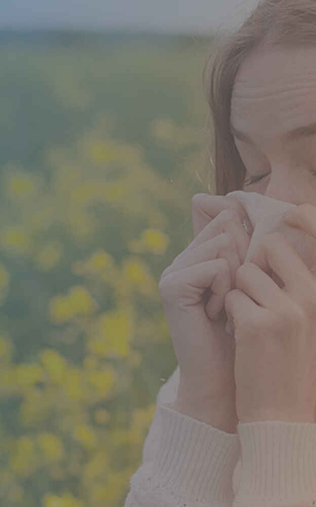 Woman sneezing into tissue due to allergies