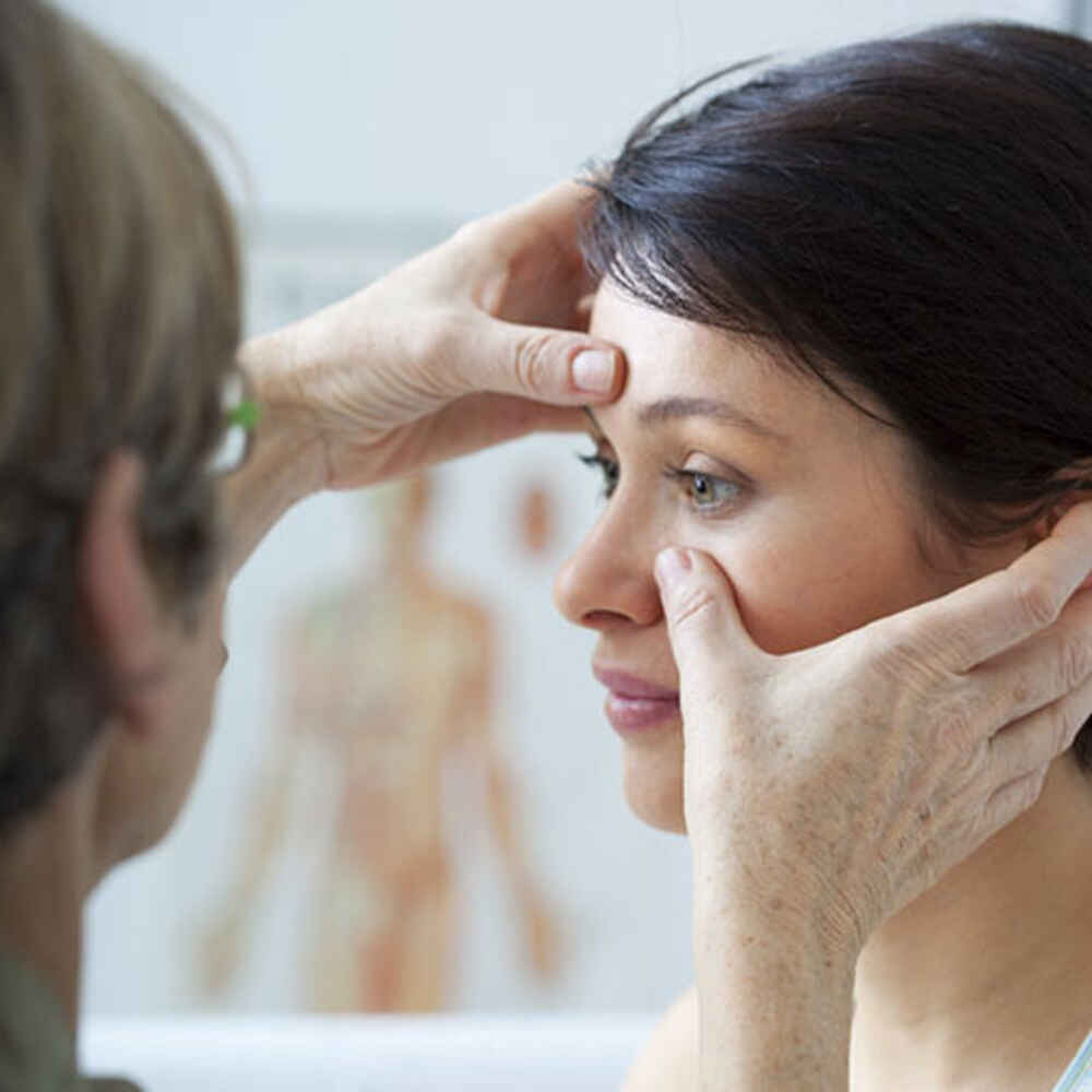 ENT doctor pressing fingers on patient's face to check for sinus issues