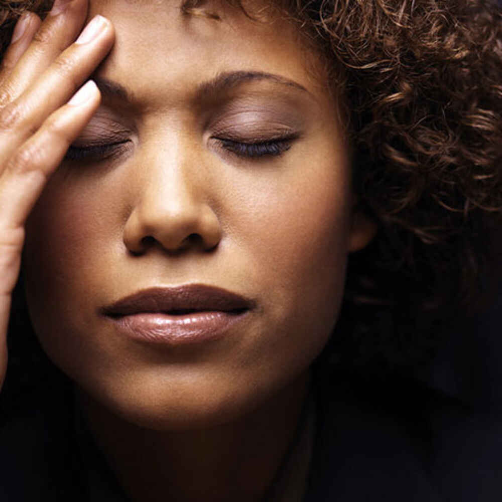 Woman with hand on head appearing to be experiencing facial pressure due to sinus issues