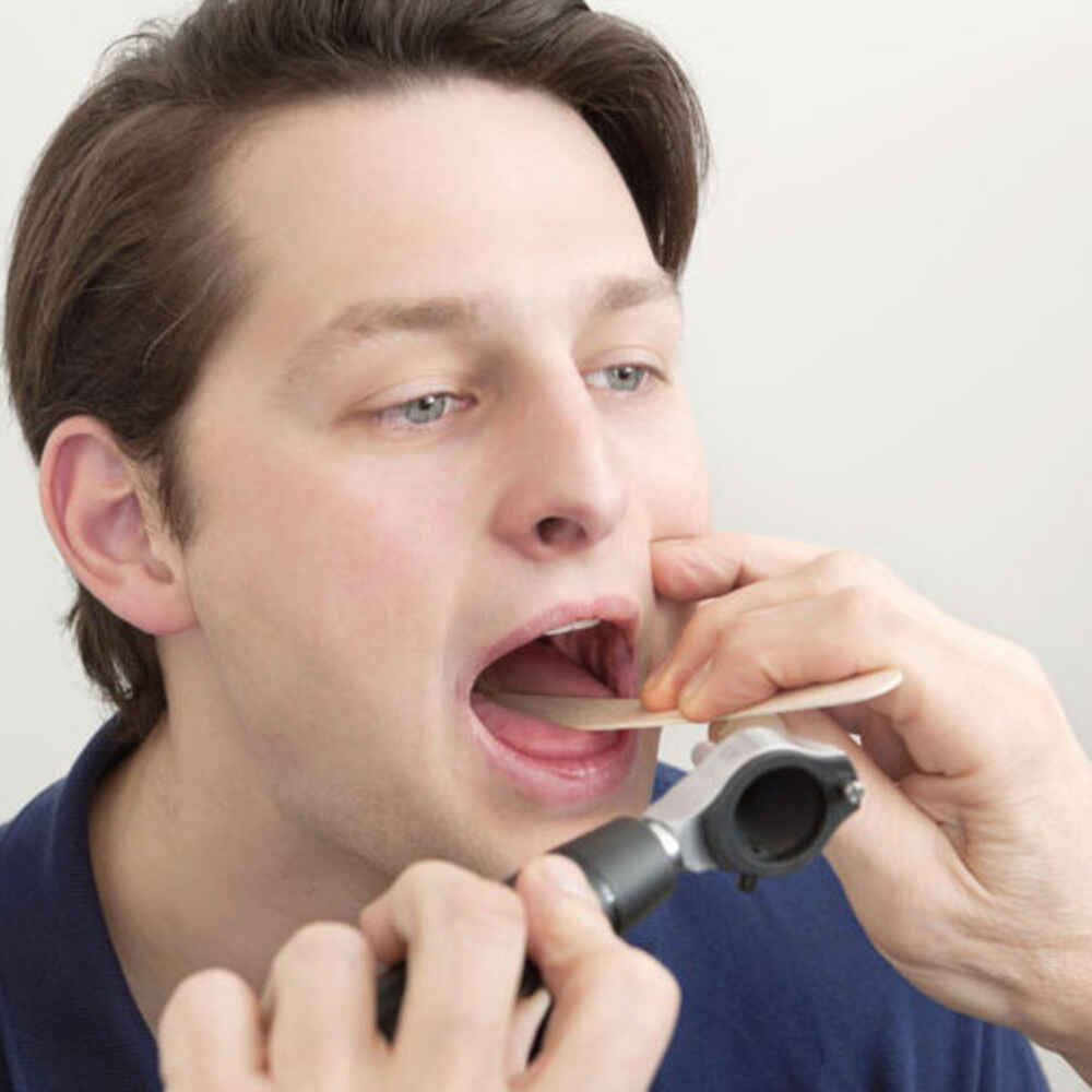ENT doctor checking inside patient's mouth for oral or throat issues