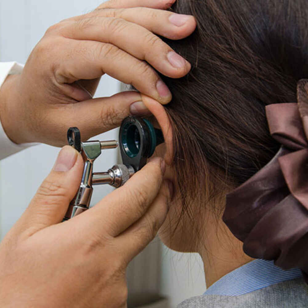 ENT doctor checking patient's ear for earwax buildup