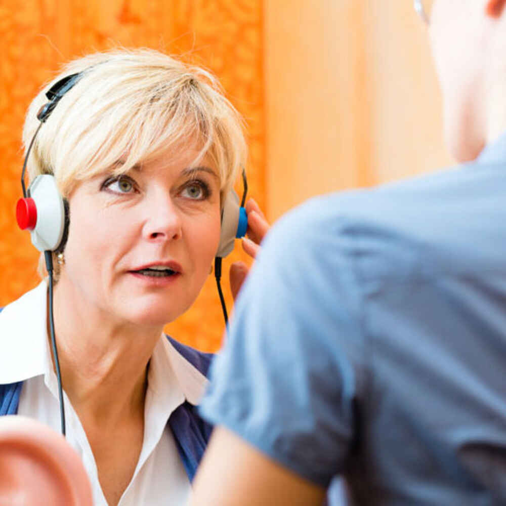 Audiologist with patient wearing headphones for hearing test