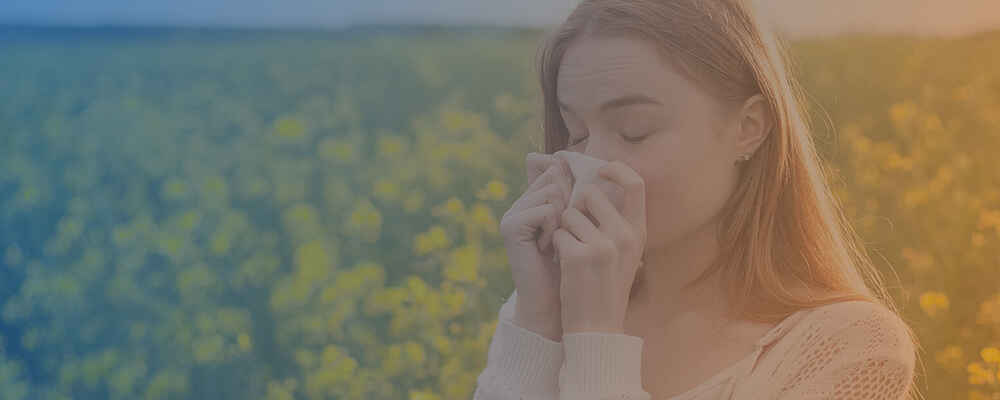 Woman sneezing into tissue due to allergies